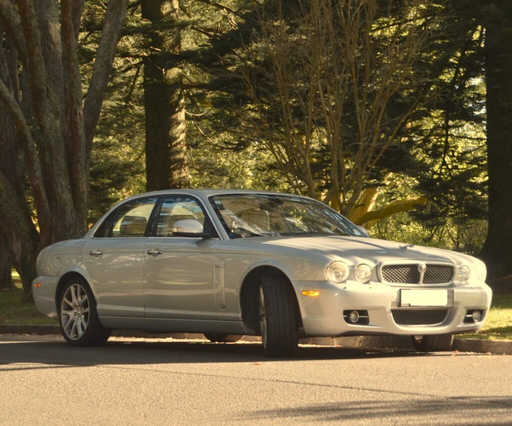 Silver Jaguar saloon parked under trees
